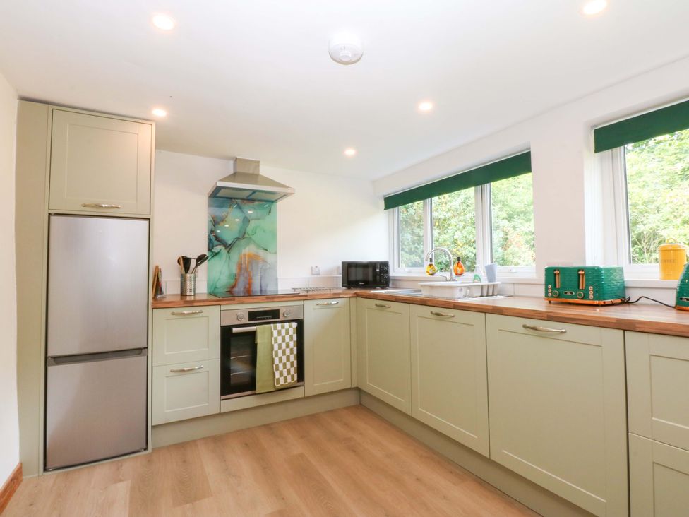 A kitchen with appliances and windows at Cromlech Cottage at Cromlech Manor Farm Tyn-y-Gongl near Benllech