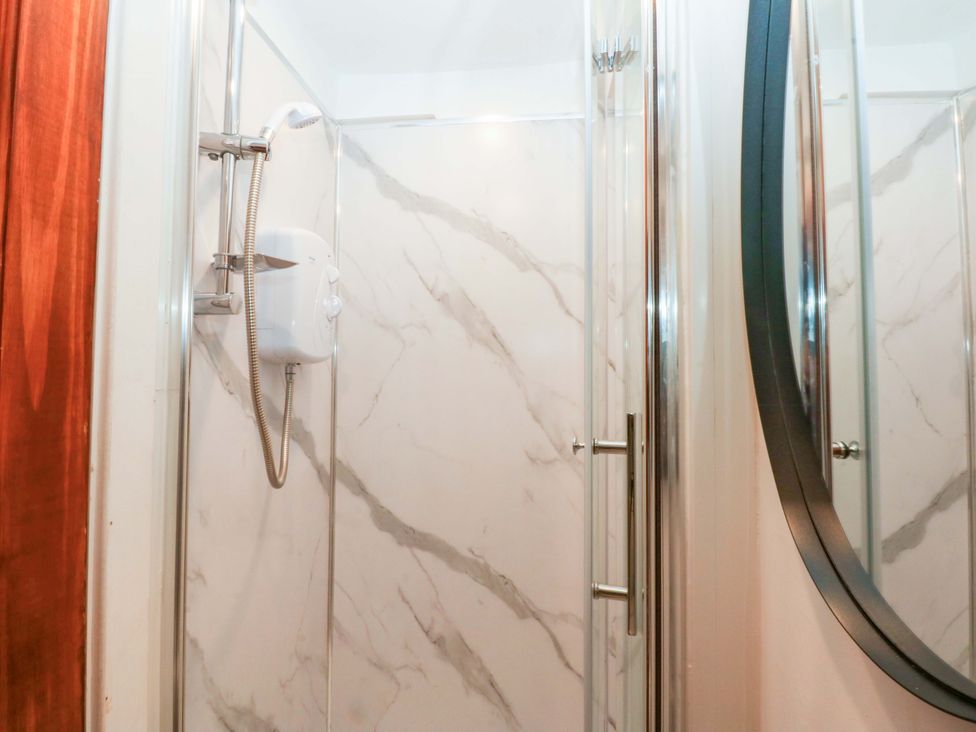 A shower with marble walls and a mirror at Cromlech Cottage at Cromlech Manor Farm near Tyn-y-Gongl