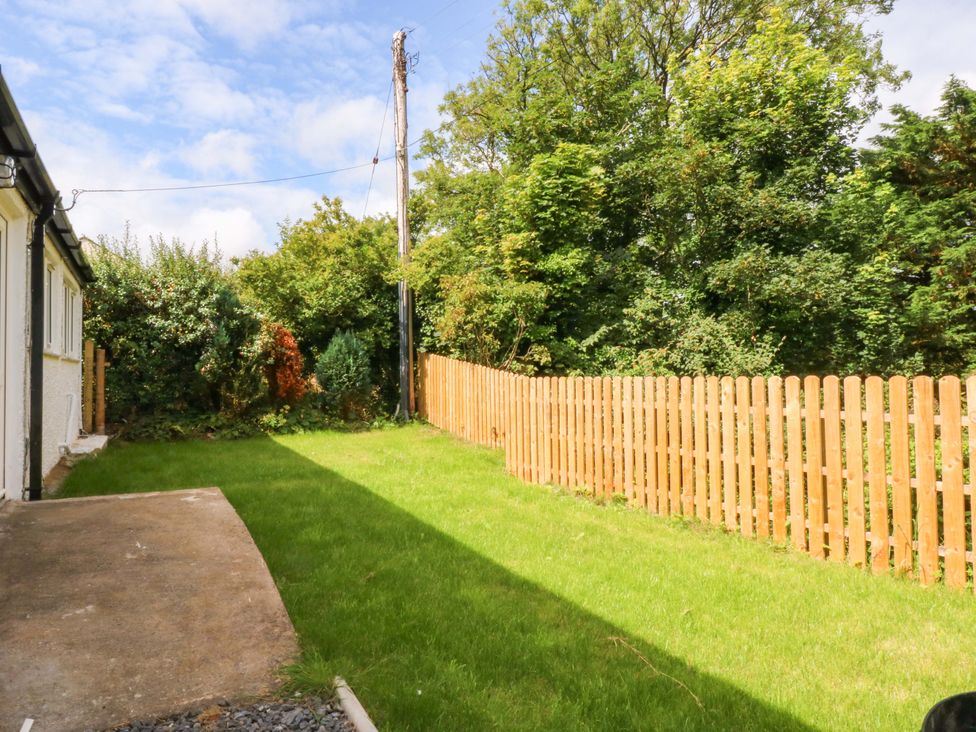 A garden with grass and a wooden fence at Cromlech Cottage at Cromlech Manor Farm, Tyn-y-Gongl near Benllech