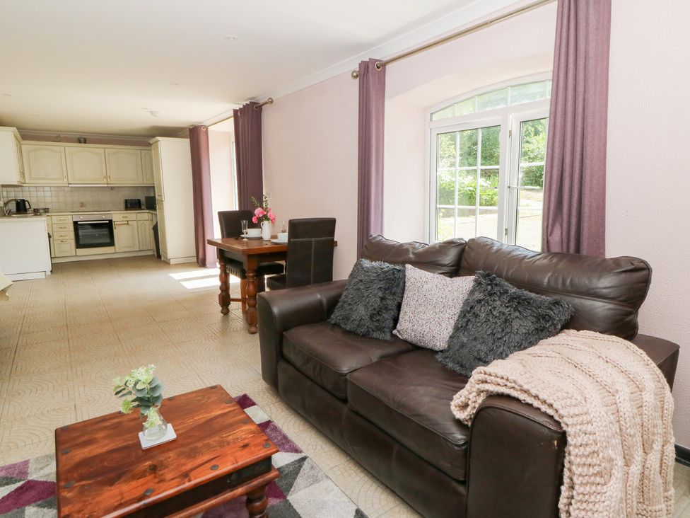 A living room with a sofa and dining table at Garden apartment in Llandysul