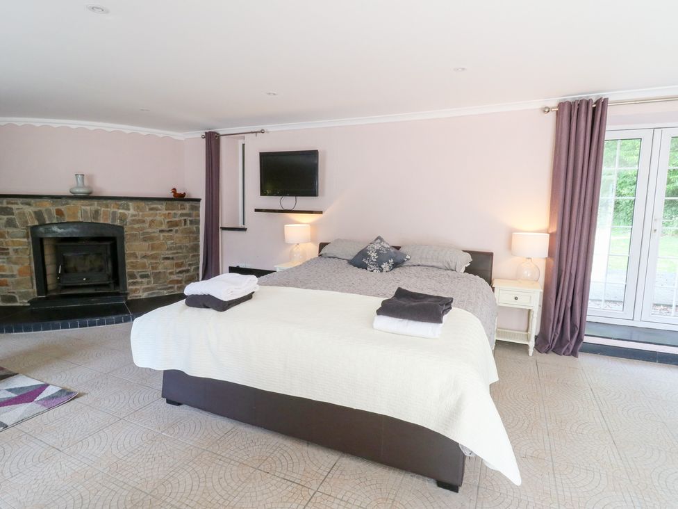 A bedroom with a bed and fireplace at Garden apartment in Llandysul