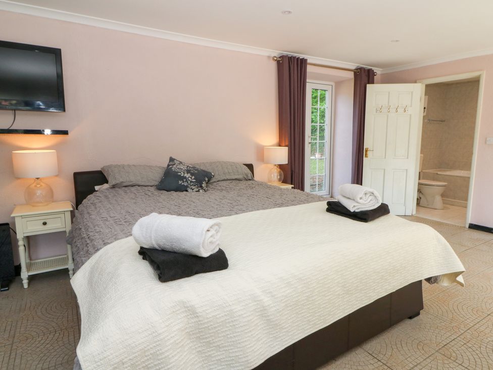 A bedroom with a double bed and ensuite bathroom at Garden apartment in Llandysul