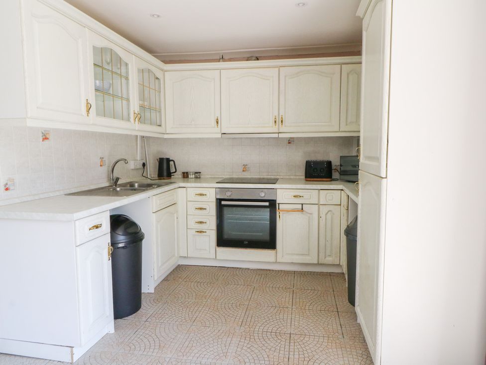 A kitchen with cabinets, sink, stove, and refrigerator at Garden apartment in Llandysul