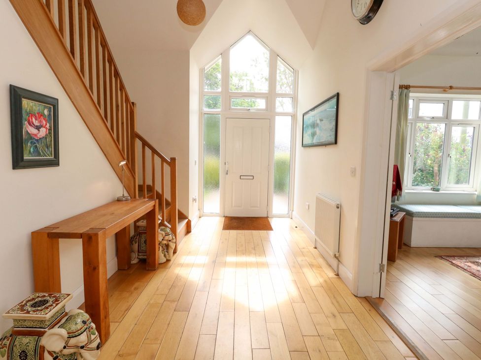 A hallway with a staircase and a console table at 1 Fernhill Avenue in Weymouth