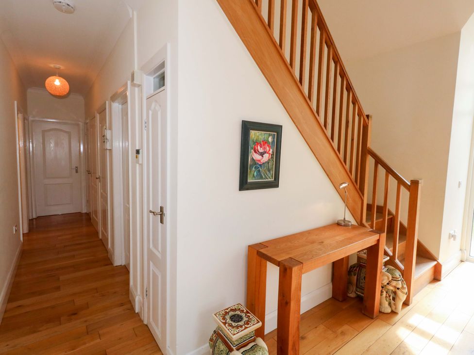 A hallway with stairs, a table, and a painting at 1 Fernhill Avenue Weymouth