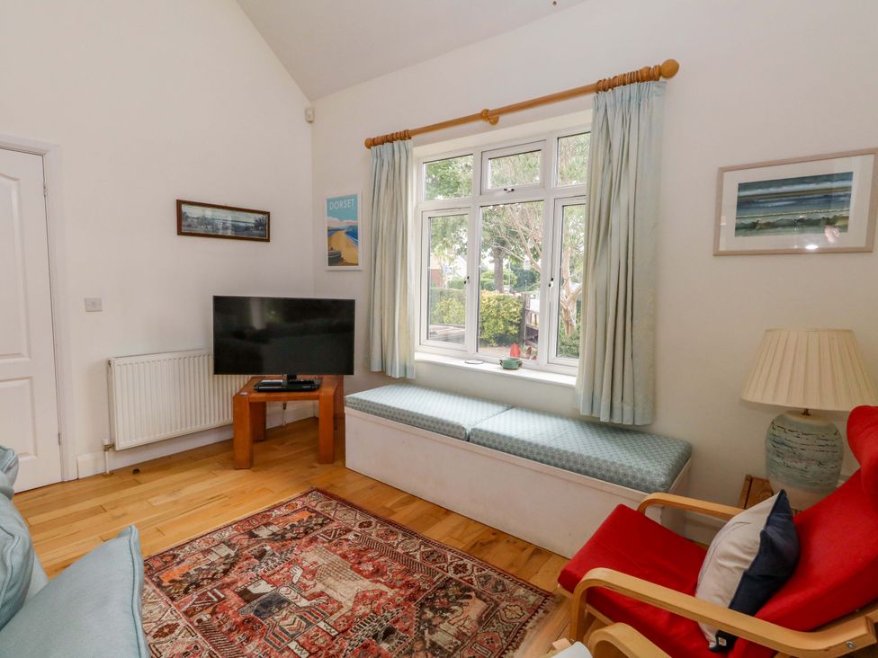 A living room with a television and window seat at 1 Fernhill Avenue Weymouth