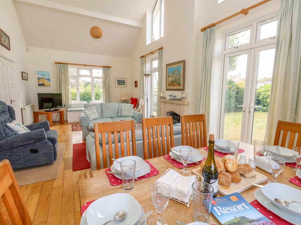 A dining room with a table set and a living area at 1 Fernhill Avenue Weymouth