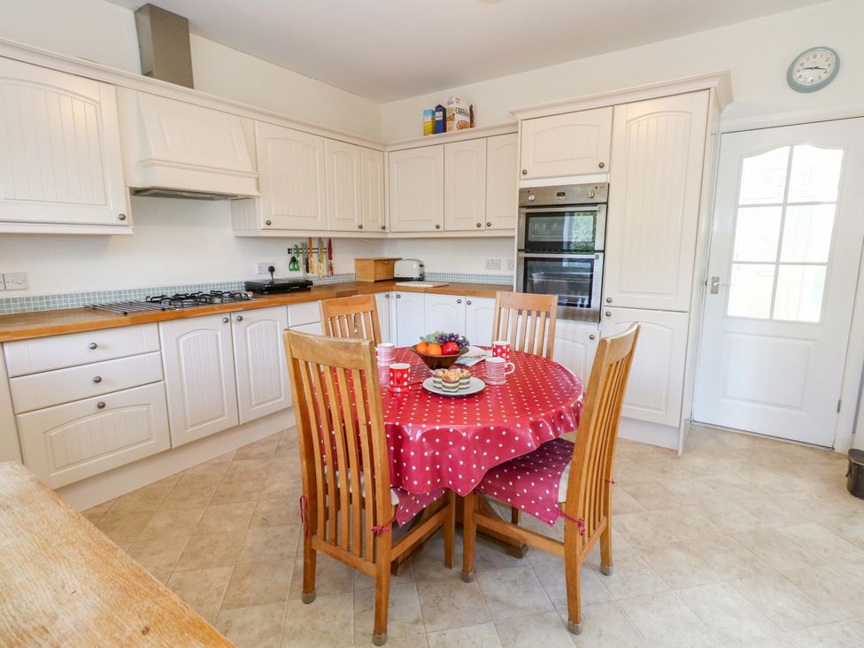 A kitchen with a dining table and appliances at 1 Fernhill Avenue Weymouth