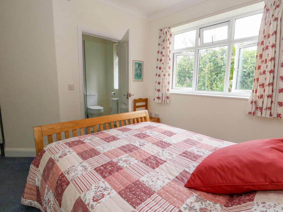 A bedroom with a bed and a door leading to a bathroom at 1 Fernhill Avenue Weymouth