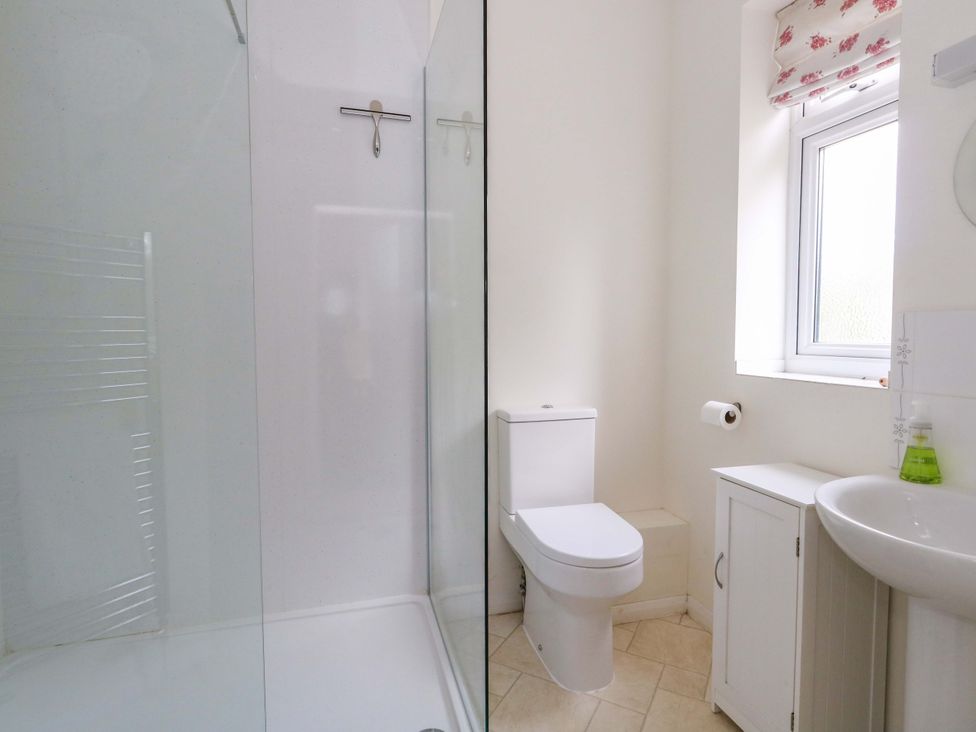 A bathroom with a shower, toilet, sink and storage cabinet at 1 Fernhill Avenue Weymouth