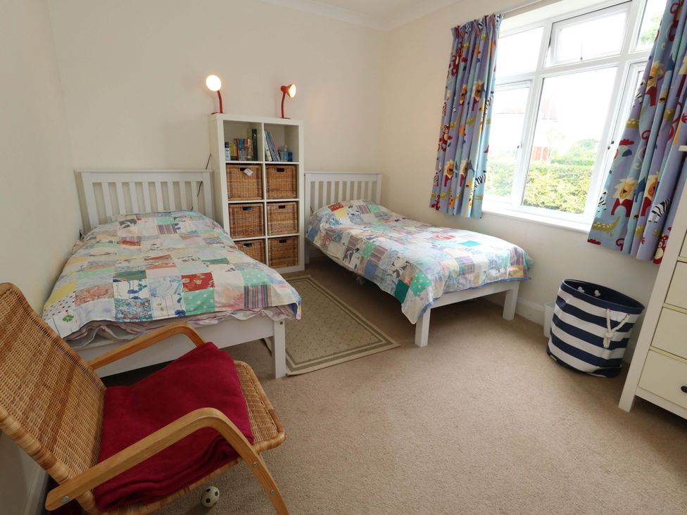 A bedroom with two beds and a bookcase at 1 Fernhill Avenue in Weymouth