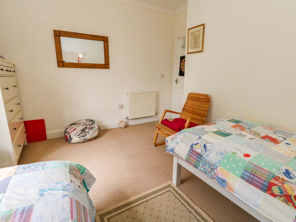 A bedroom with beds and a chair at 1 Fernhill Avenue in Weymouth