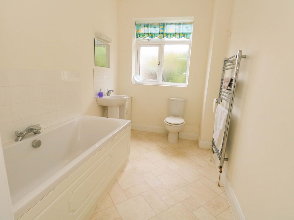 A bathroom with a bathtub, sink, and toilet at 1 Fernhill Avenue Weymouth