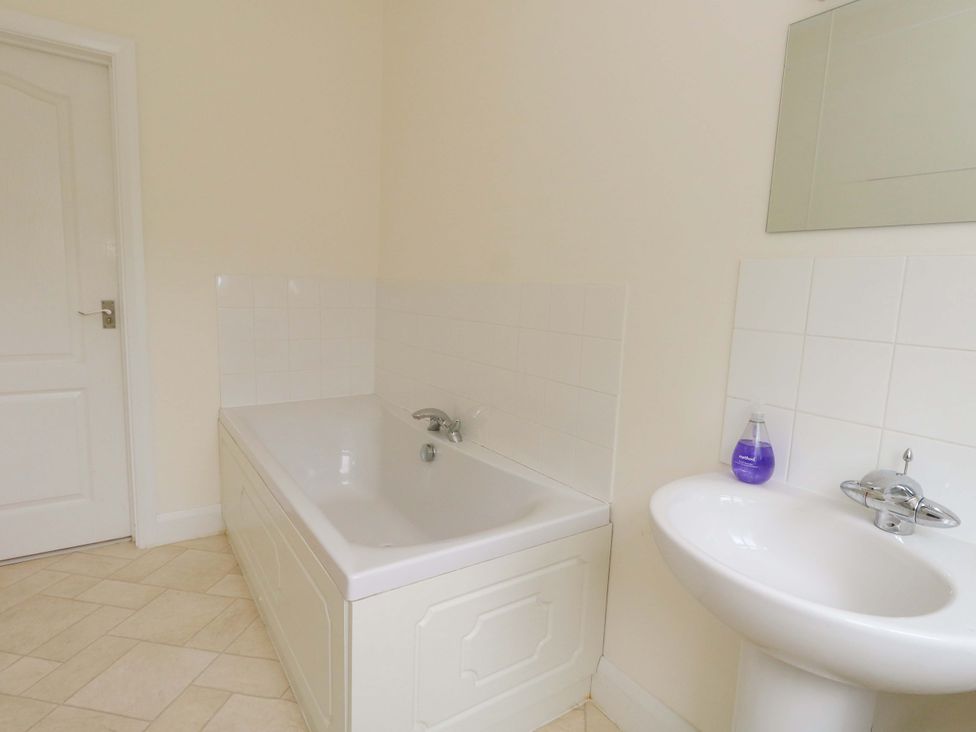 A bathroom with a bathtub and a sink at 1 Fernhill Avenue Weymouth