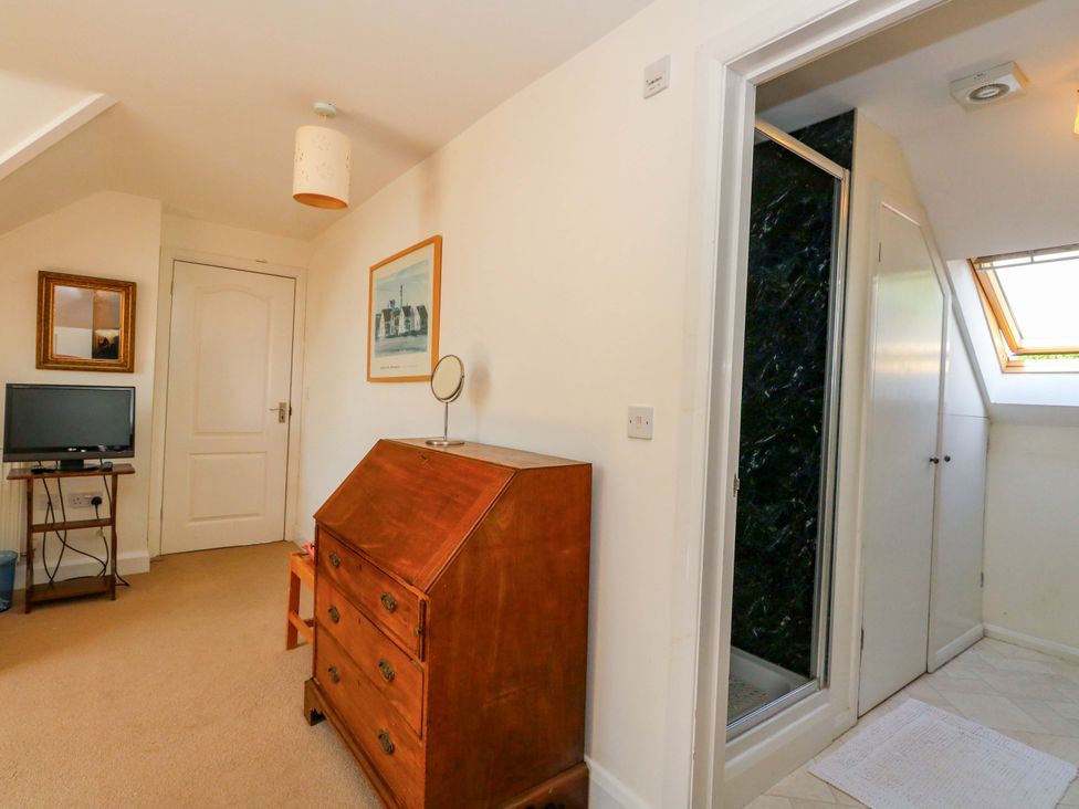 A bedroom with a mirror and television at 1 Fernhill Avenue in Weymouth