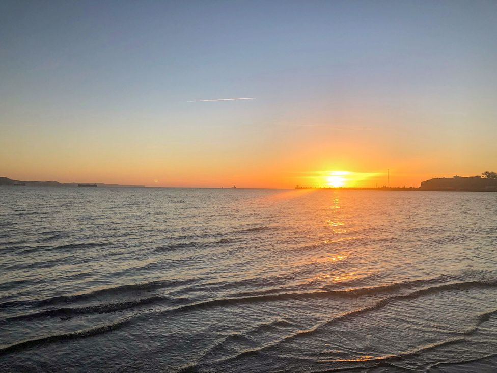 A sunset over the sea with visible waves at 1 Fernhill Avenue Weymouth