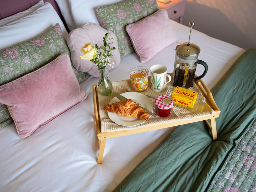 A breakfast tray on a bed with coffee and pastries at Ystrad Wen Llysdinam near Newbridge-On-Wye