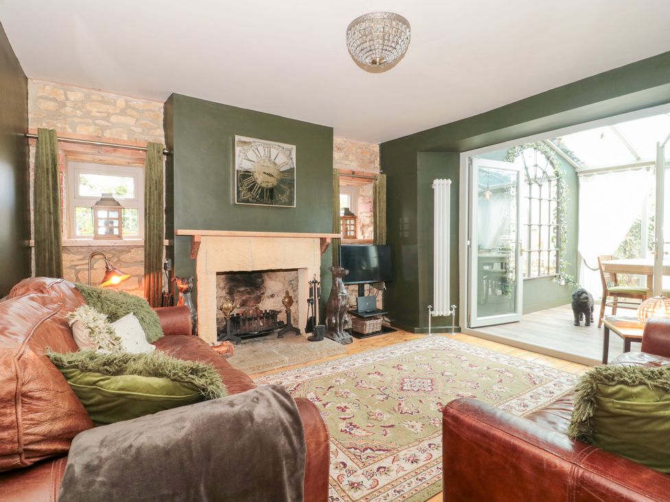 A living room with a fireplace and sofa at Yarn Cottage in Broadway