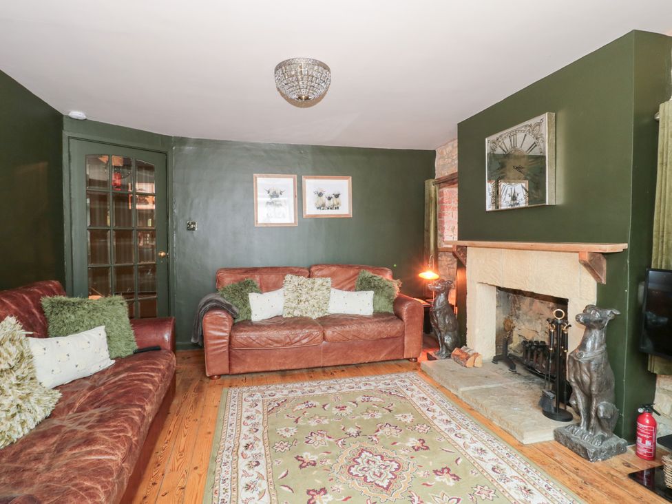 A living room with a fireplace and sofas at Yarn Cottage in Broadway