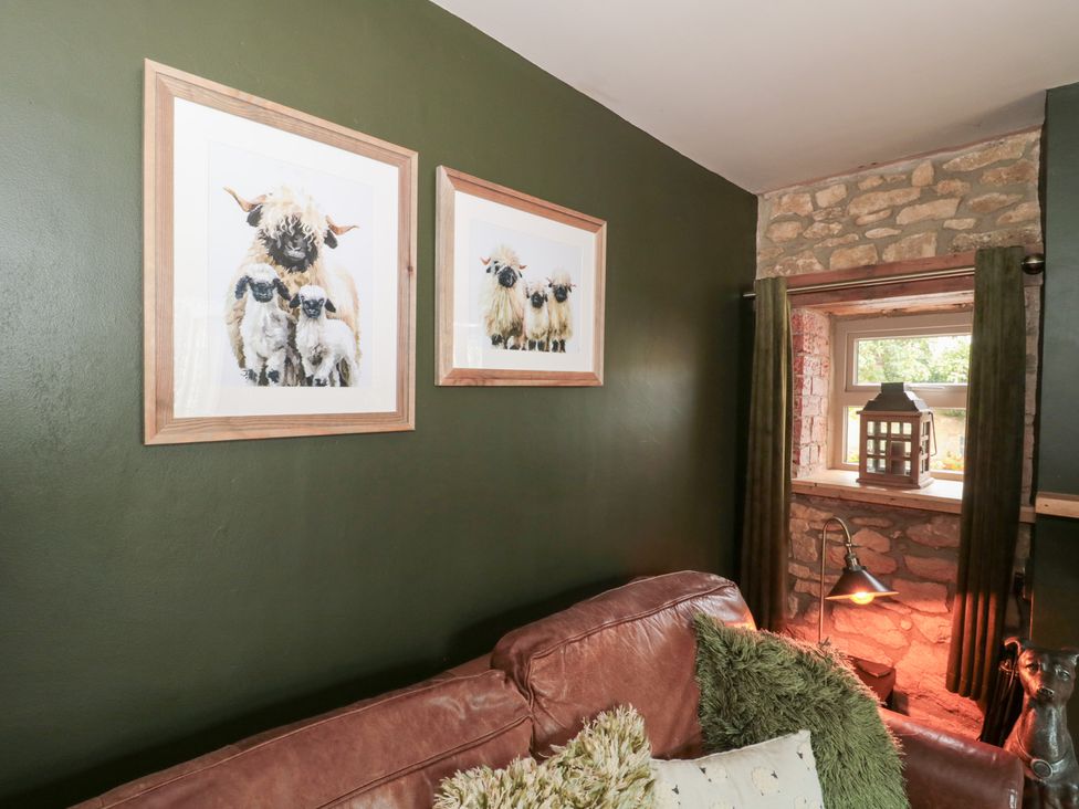 A living room with framed pictures and a sofa at Yarn Cottage in Broadway