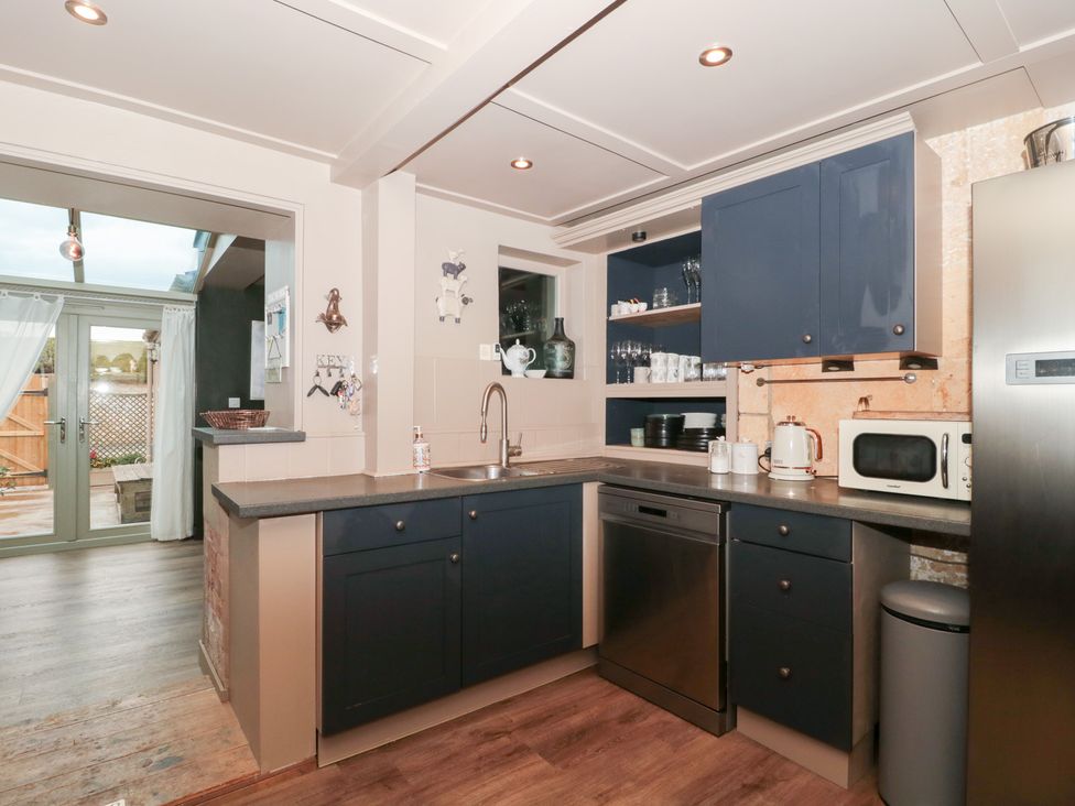 A kitchen with appliances and cabinets at Yarn Cottage in Broadway