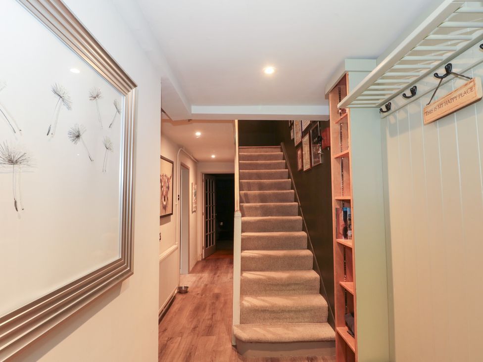 A hallway with a staircase and wall art at Yarn Cottage in Broadway