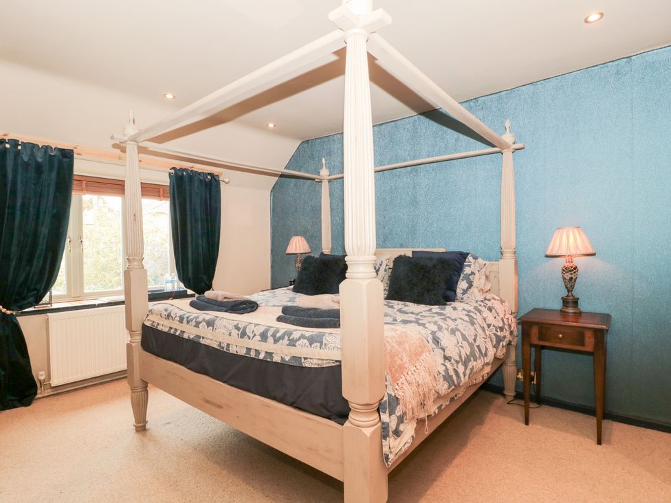 A bedroom with a four-poster bed and a nightstand at Yarn Cottage in Broadway