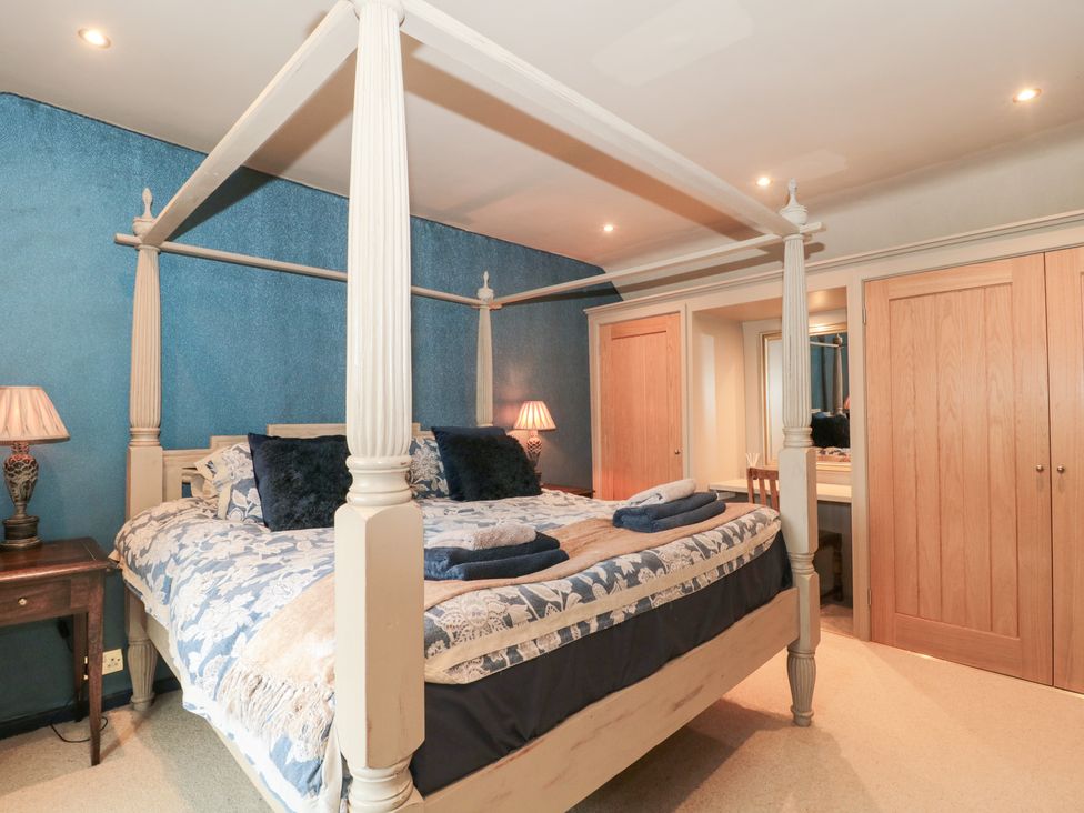 A bedroom with a four-poster bed and wardrobe at Yarn Cottage in Broadway