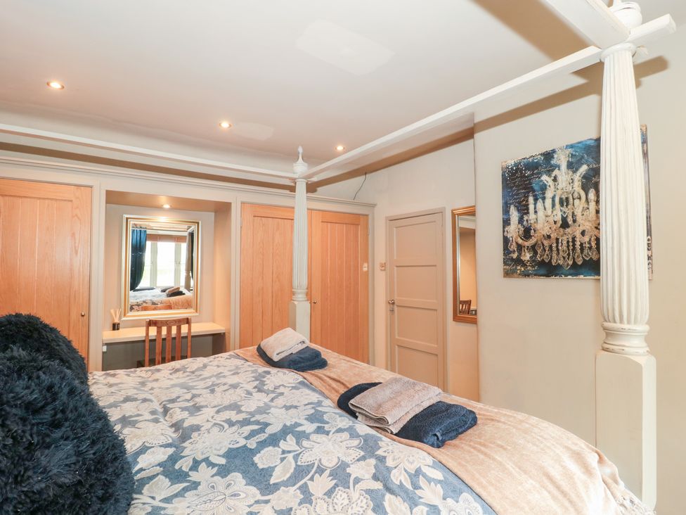 A bedroom with a bed and a mirror at Yarn Cottage in Broadway
