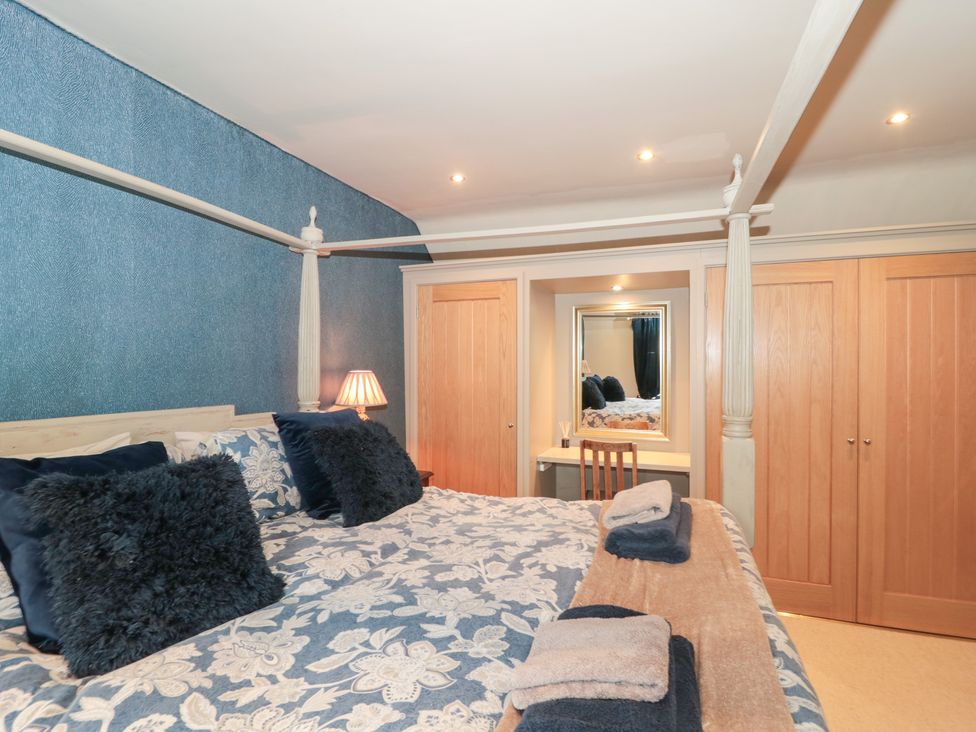 A bedroom with a double bed and a mirror at Yarn Cottage in Broadway
