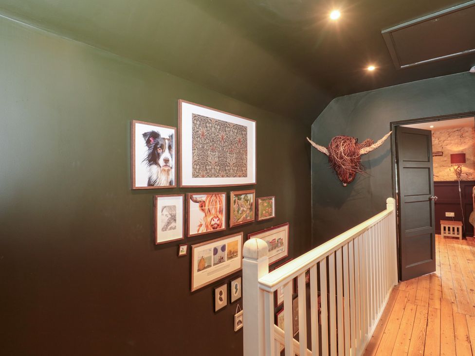 A hallway with framed artwork on the walls at Yarn Cottage in Broadway