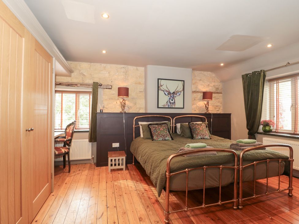 A bedroom with a bed and a chair at Yarn Cottage Broadway