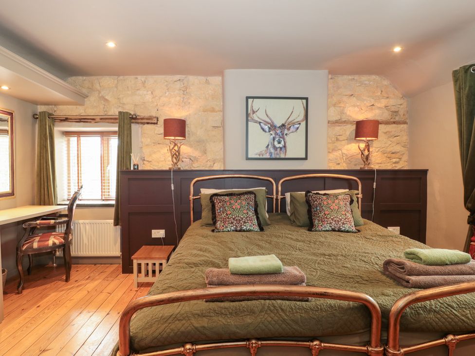 A bedroom with a bed and desk at Yarn Cottage in Broadway