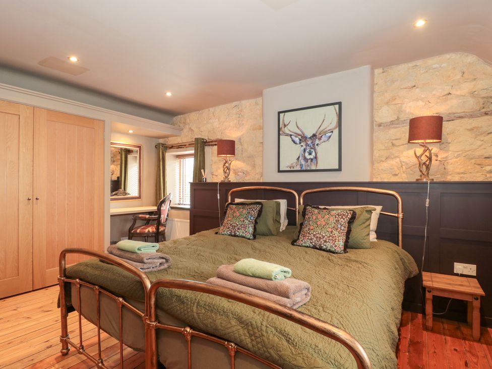 A bedroom with a bed and a mirror at Yarn Cottage in Broadway
