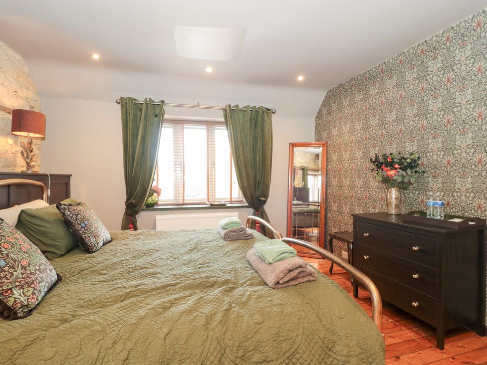A bedroom with a bed and mirror at Yarn Cottage in Broadway