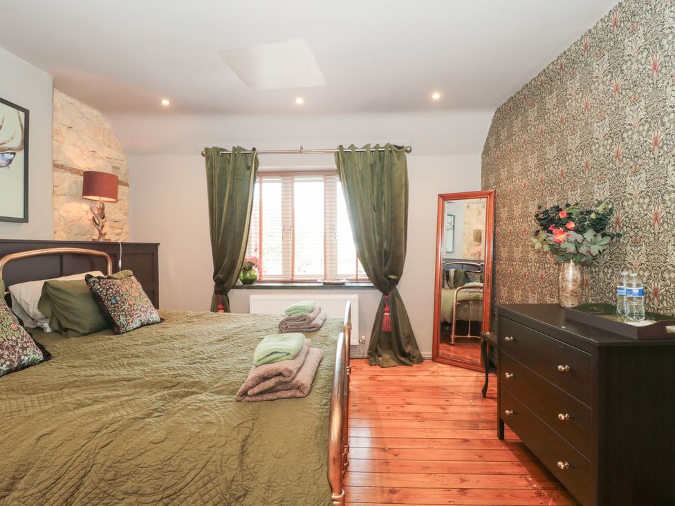 A bedroom with a bed and window at Yarn Cottage in Broadway
