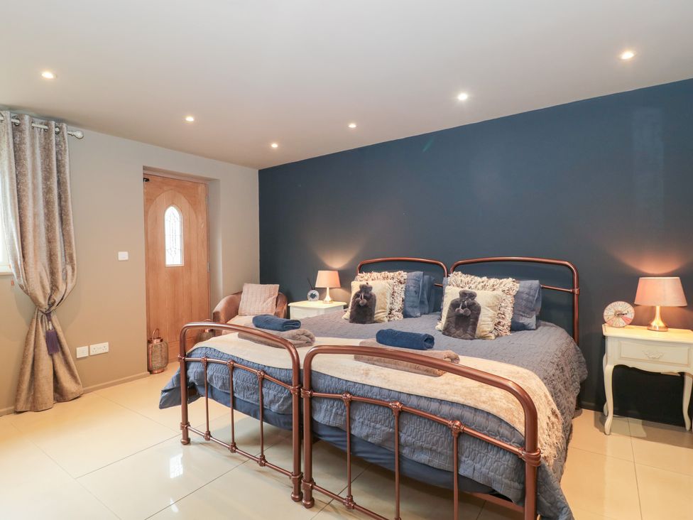 A bedroom with two beds and a nightstand at Yarn Cottage in Broadway