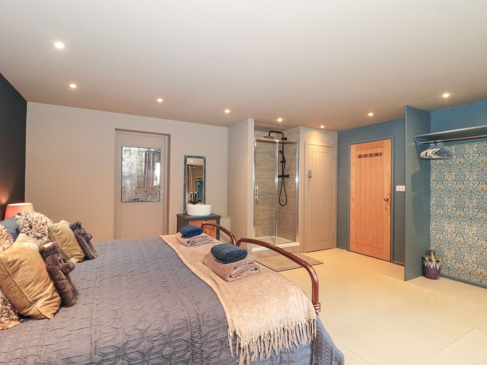 A bedroom with a bed and shower at Yarn Cottage in Broadway