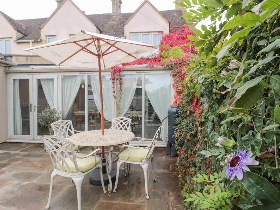 A garden with a table and chairs under an umbrella at Yarn Cottage in Broadway