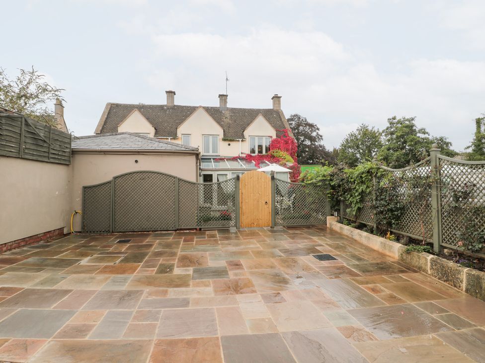 A garden with paving stones and a wooden gate at Yarn Cottage in Broadway