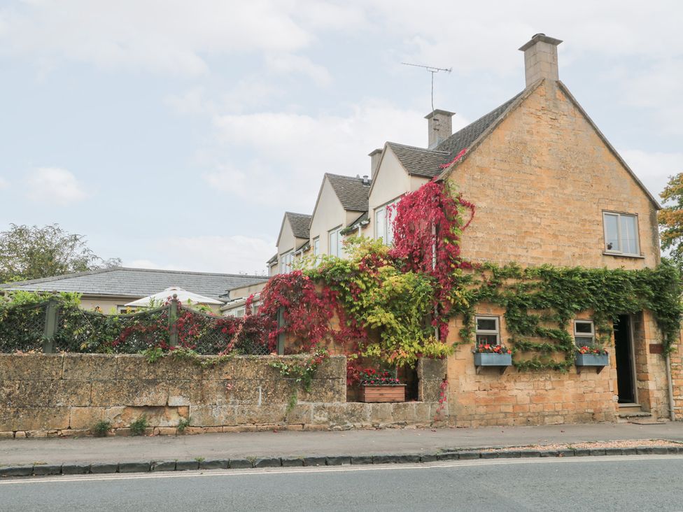 A house with plants on the walls and a brick wall outside at Yarn Cottage in Broadway