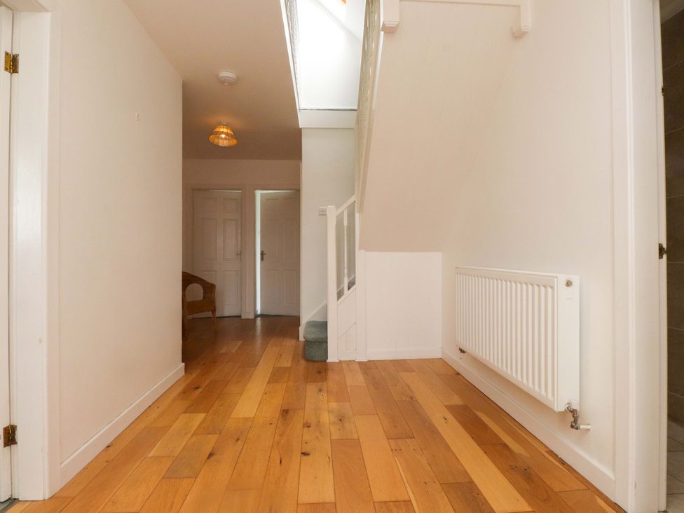 A hallway with a staircase and wooden flooring at Belan Wen in Llanddona near Pentraeth
