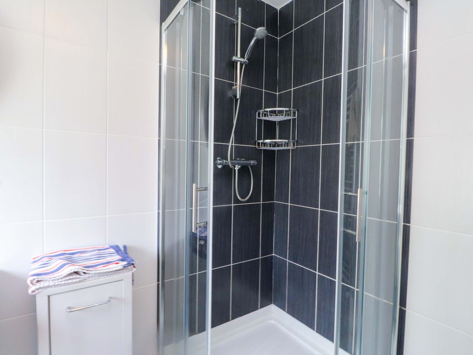 A shower with glass doors and towels in a bathroom at Belan Wen in Llanddona near Pentraeth