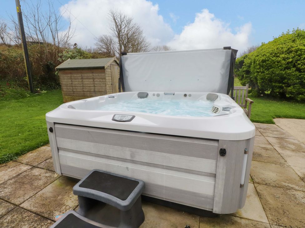 A hot tub with steps and a shed in the garden at Belan Wen in Llanddona near Pentraeth