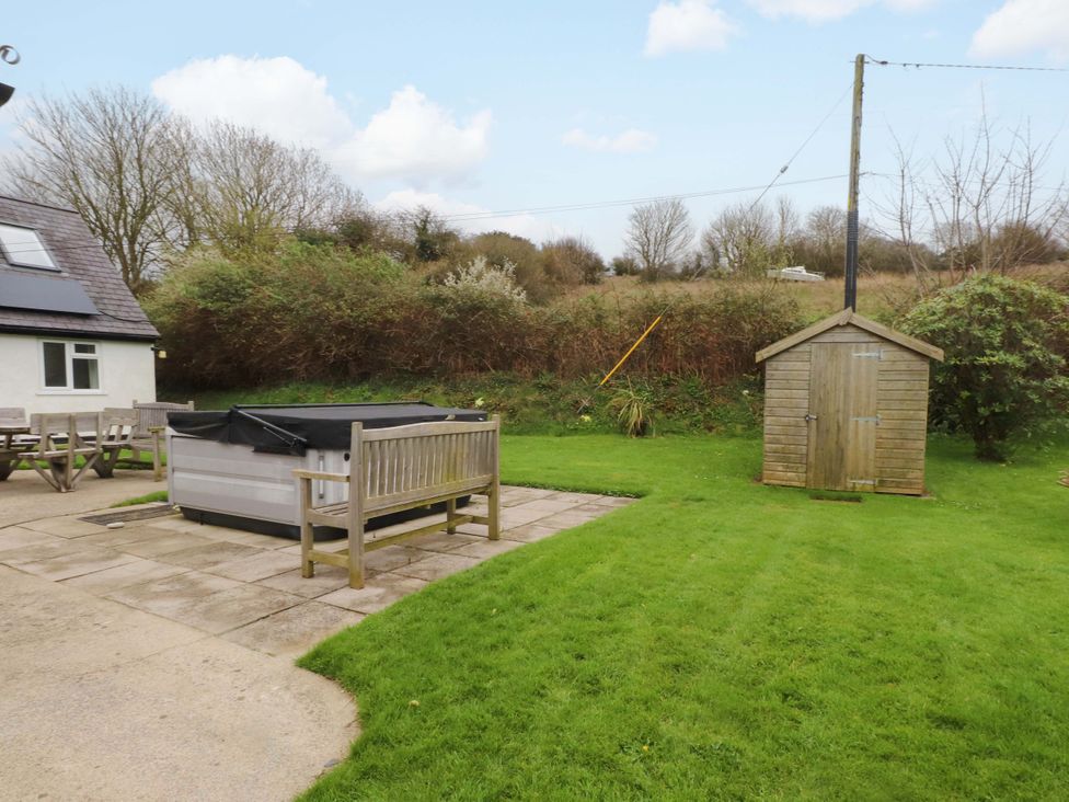 A garden with a hot tub and a wooden shed at Belan Wen in Llanddona near Pentraeth
