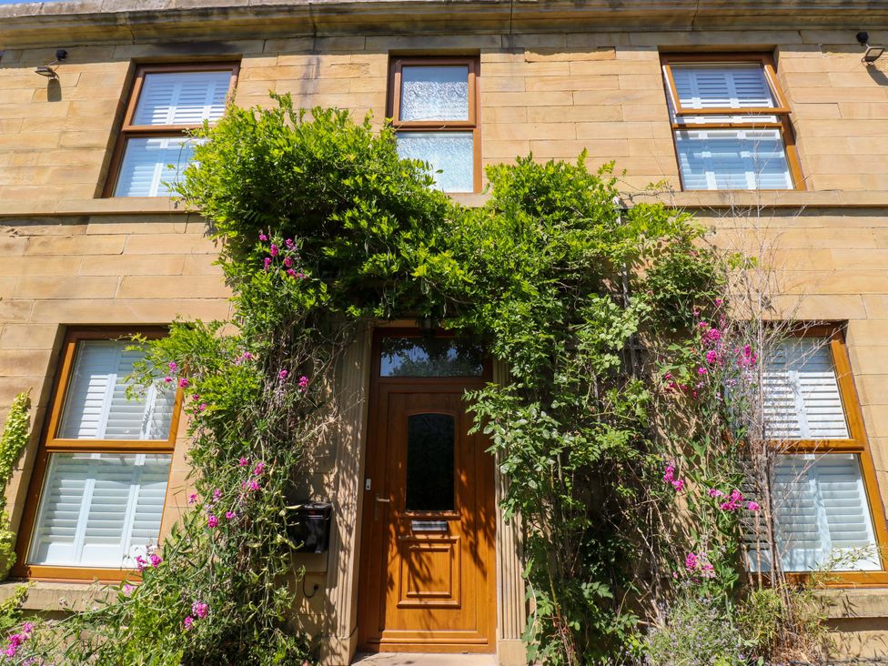 A house with wooden door and windows surrounded by plants and flowers at The Old Post Office - Pet Friendly Group Stays in Holmfirth