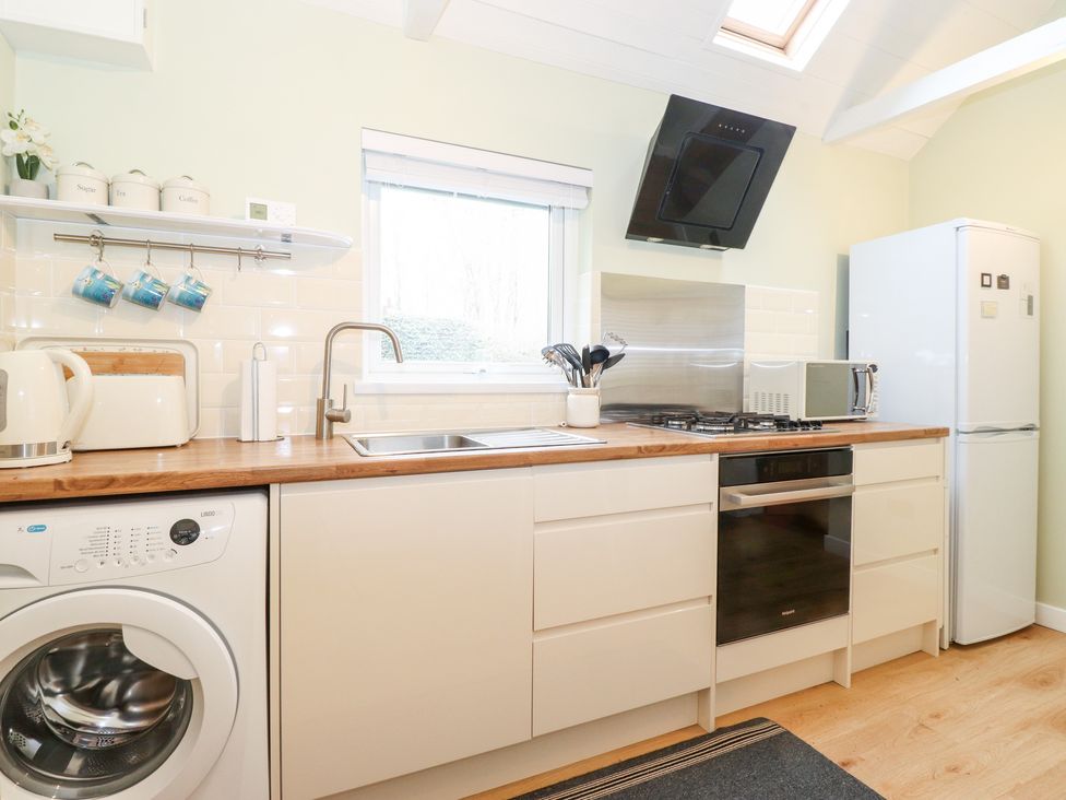 A kitchen with a washing machine sink stove oven microwave and fridge at Canny Cottage in Low Hauxley Nr Amble