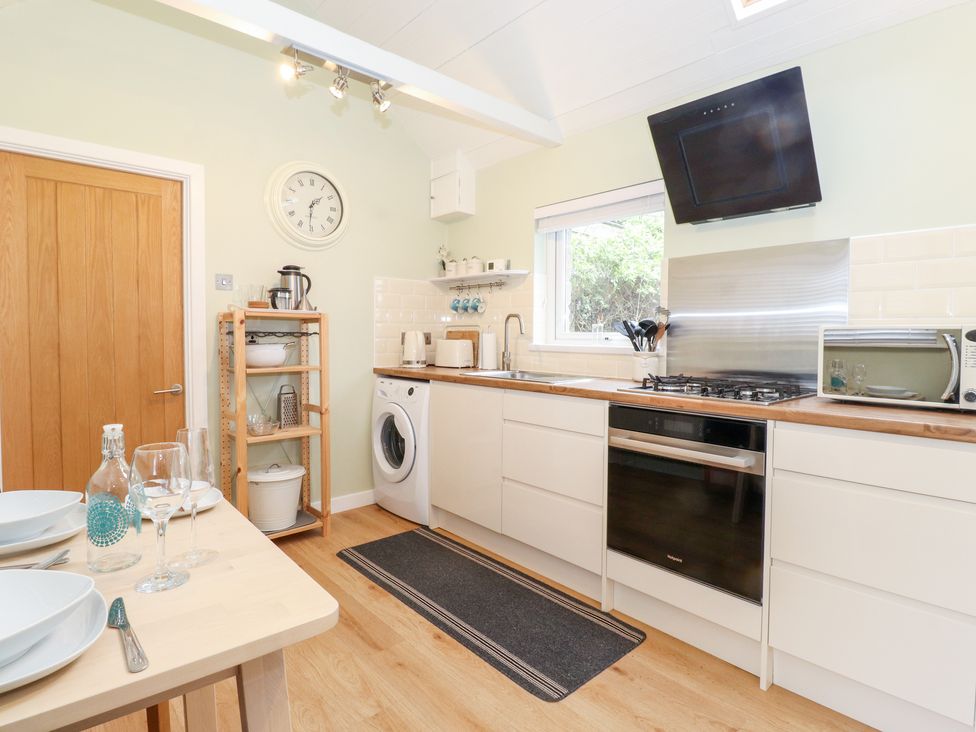 A kitchen with wooden shelves dishwasher oven and dining table at Canny Cottage Low Hauxley Nr Amble