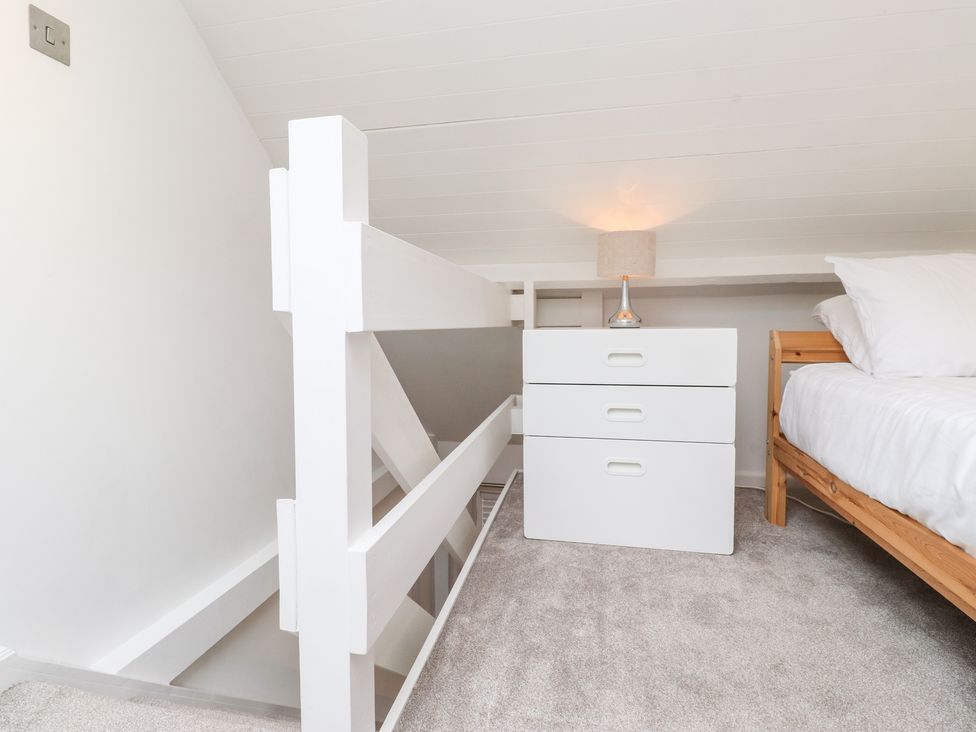 A small bedroom with a wooden bed white bedside table and a lamp at Canny Cottage Low Hauxley Nr Amble