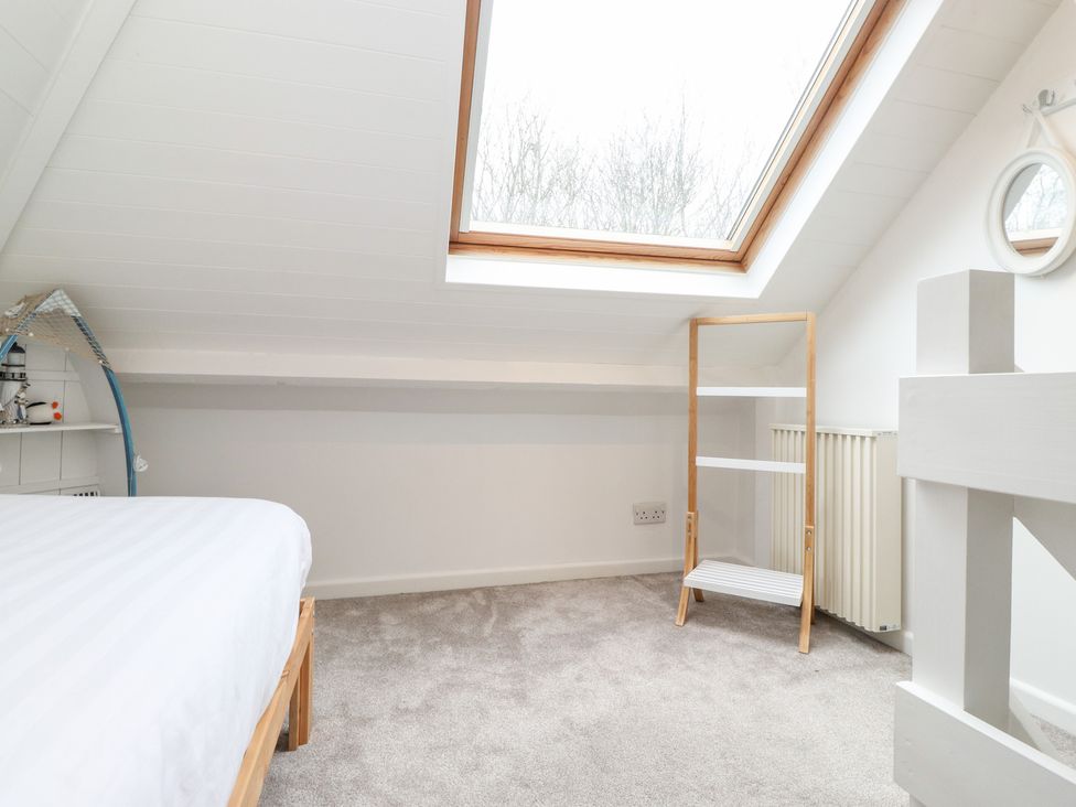 A bedroom with a skylight window a bed and a wooden white shelf at Canny Cottage in Low Hauxley Nr Amble